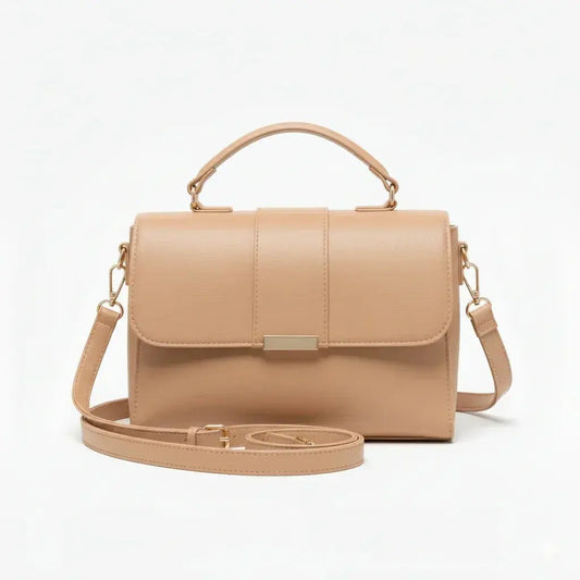 Beige leather crossbody handbag with top handle and gold hardware on white background