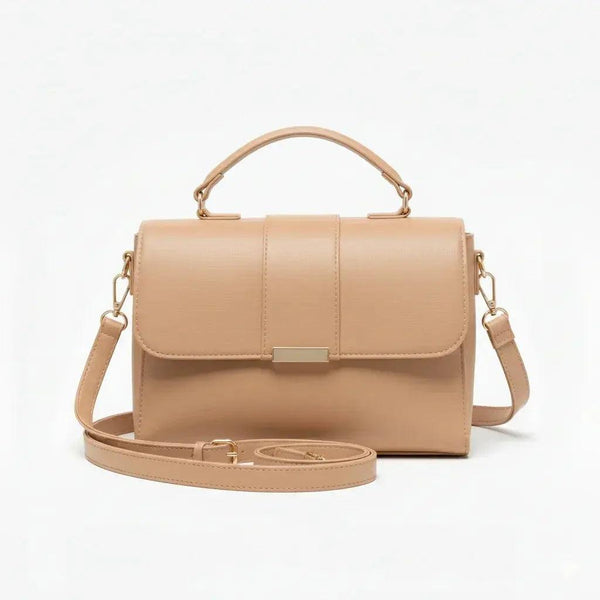 Beige leather crossbody handbag with top handle and gold hardware on white background
